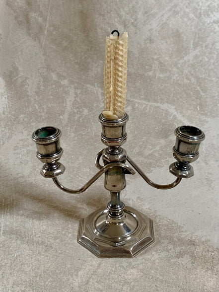 Close detail of stepped octagonal base on silver plate three-light candelabra