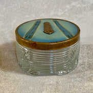 Gilt cartouche detail on powder blue enamel lid of Art Deco pressed glass jar — 1925–1935