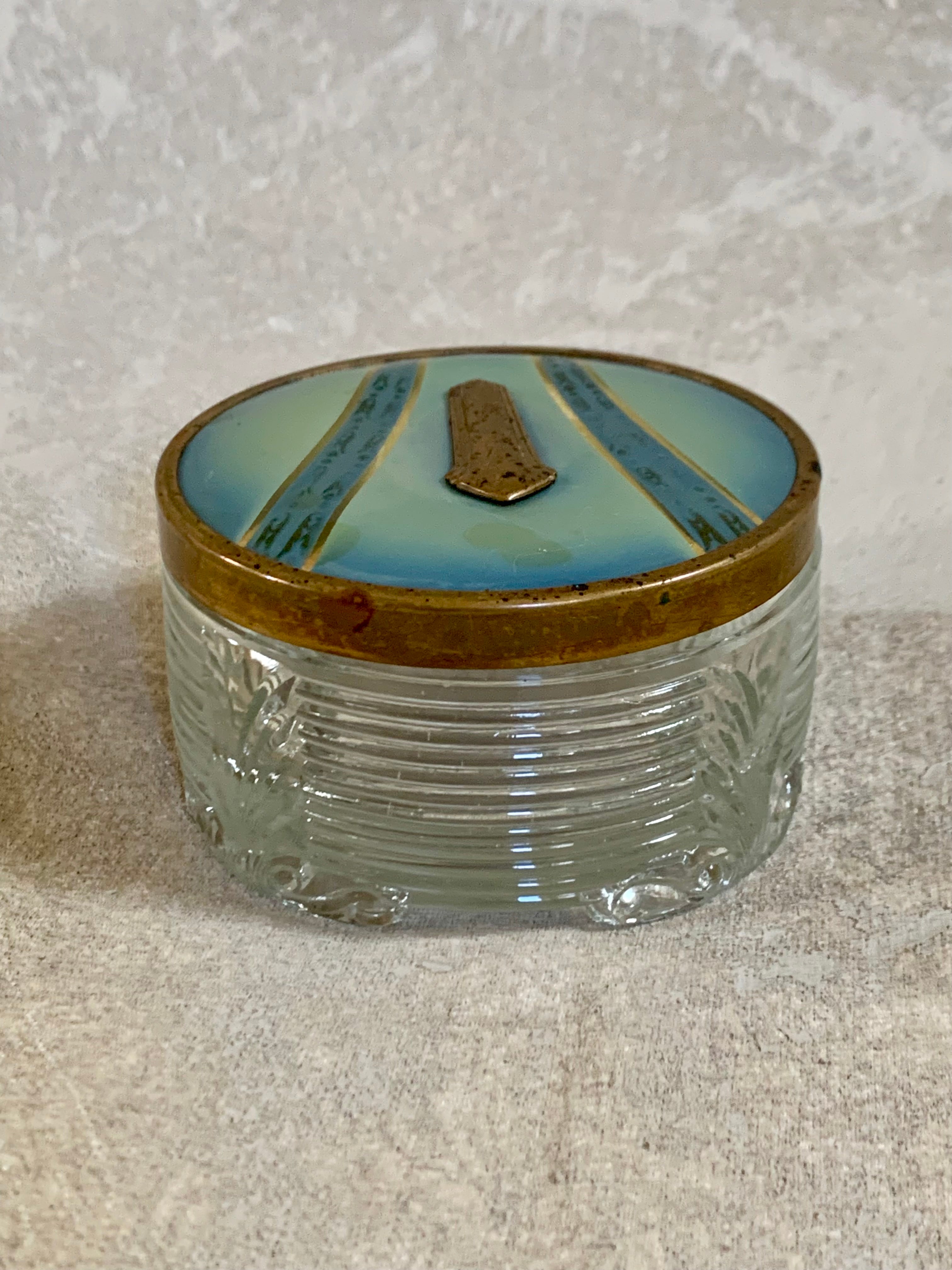 Gilt cartouche detail on powder blue enamel lid of Art Deco pressed glass jar — 1925–1935